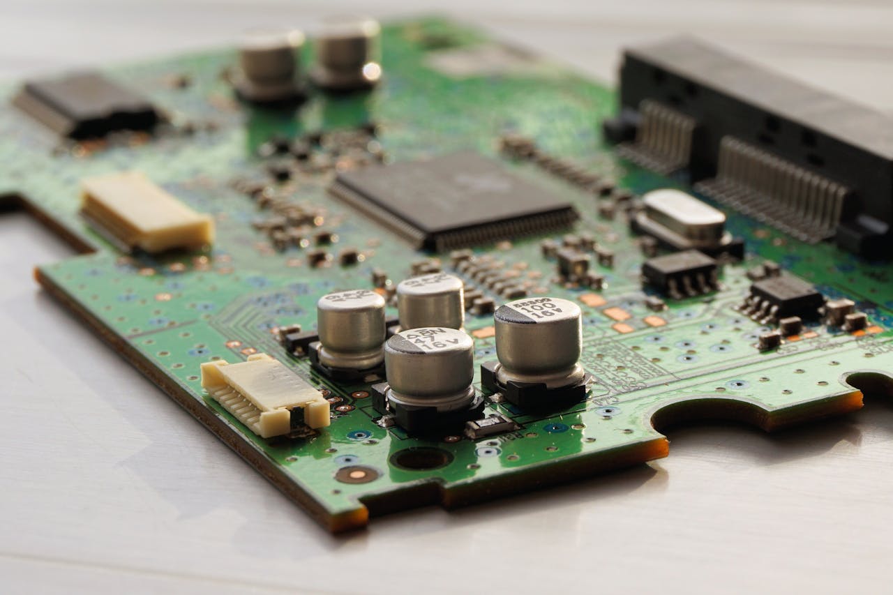 Resources Detailed view of a green circuit board featuring capacitors and microchips.